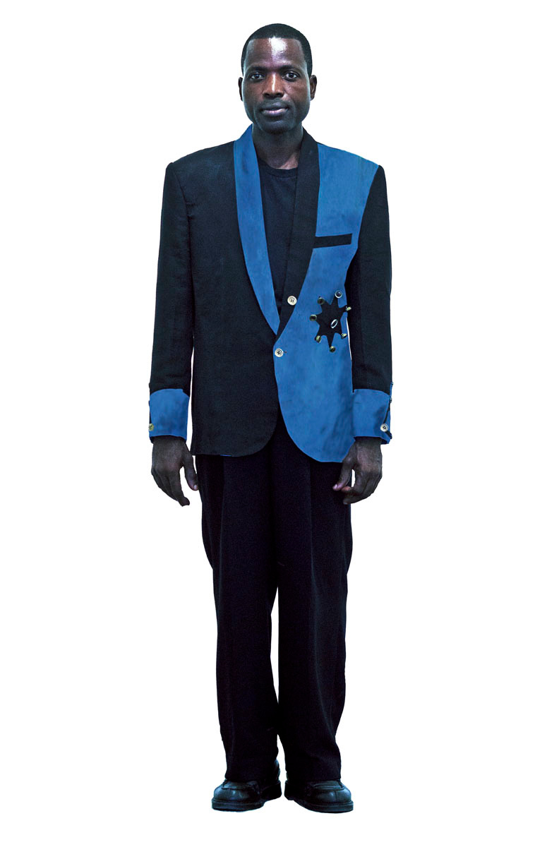 Portrait en pied de Pume Bylex dans un costume bleu et noir
