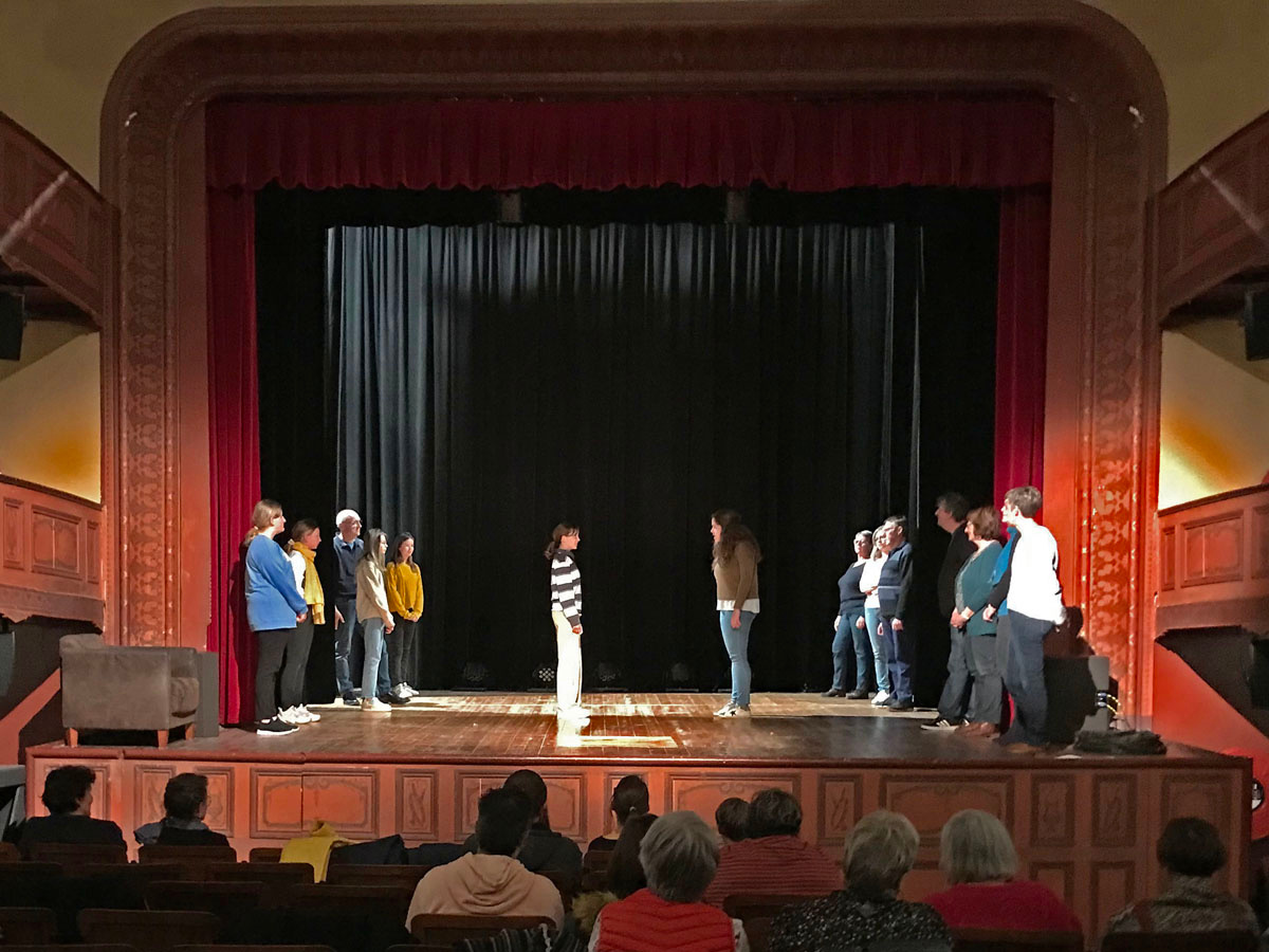 Un groupe d'hommes et de femmes sur la scène du théâtre du Familistère