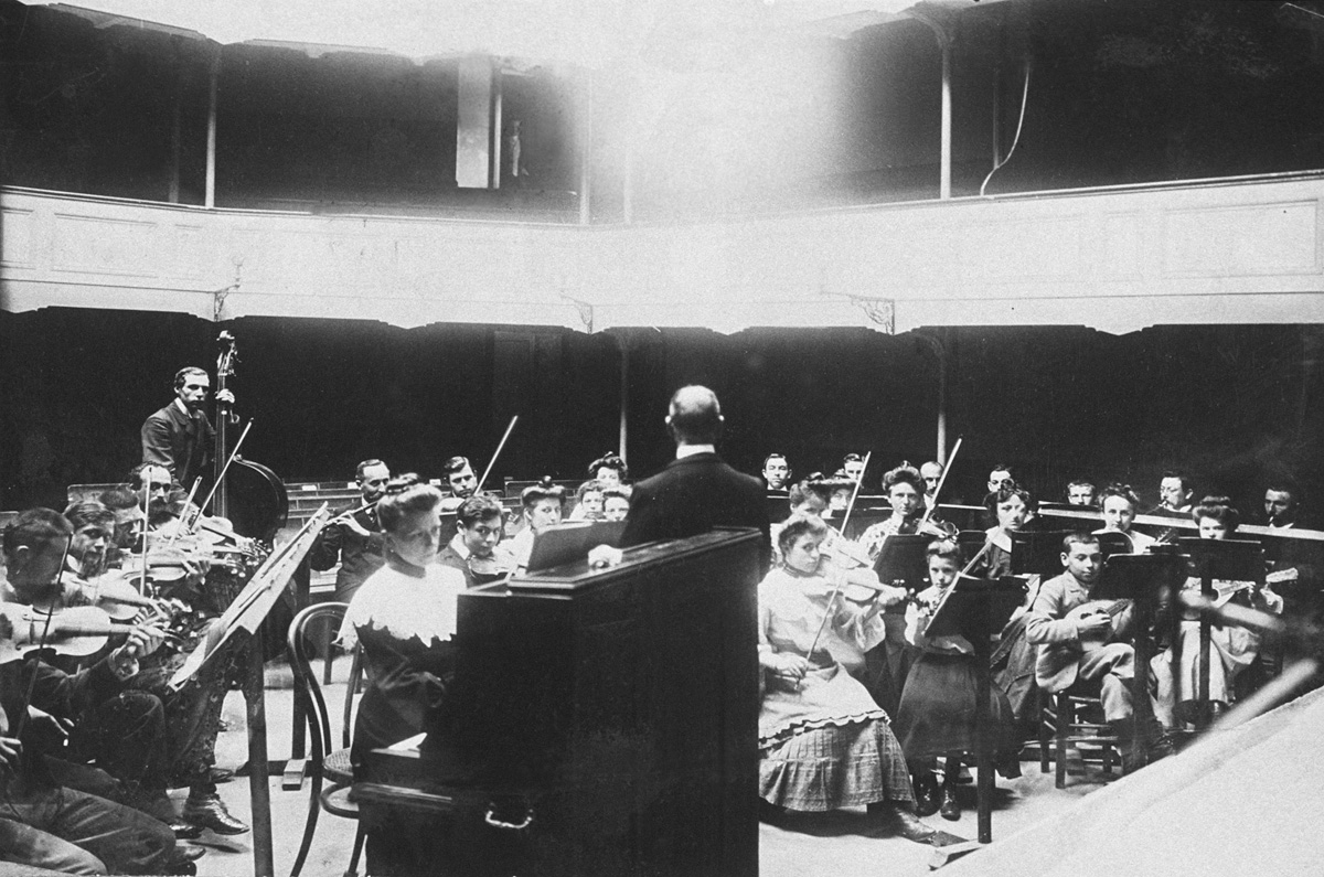 La photographie montre une répétition de l'orchestre au théâtre du Familistère