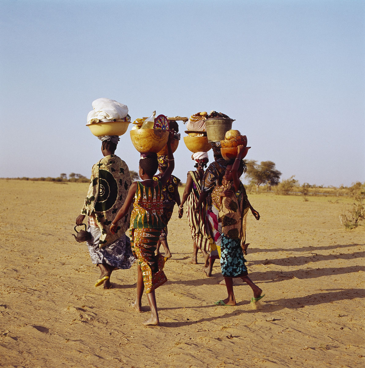 La photographie montre quatre femmes marchant dans le sable.