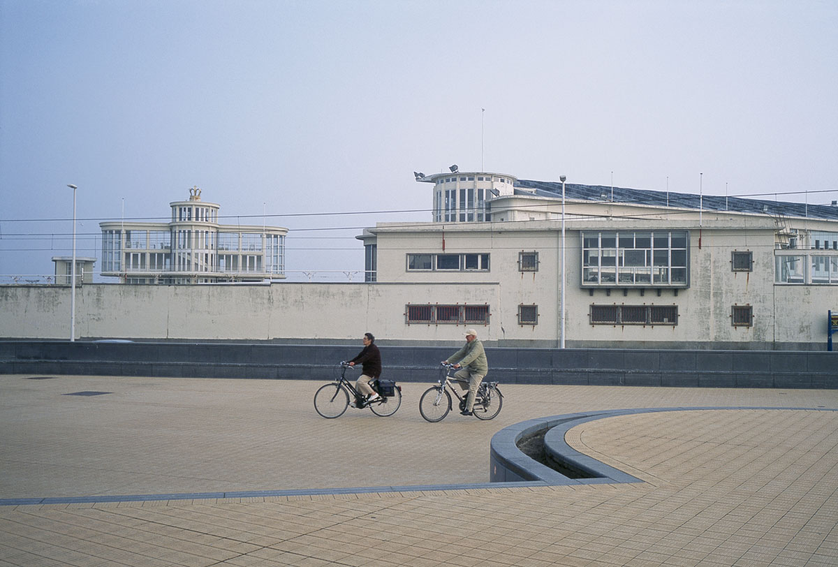 La photographie montre un couple en vélo sur un quai du port d'Ostende.